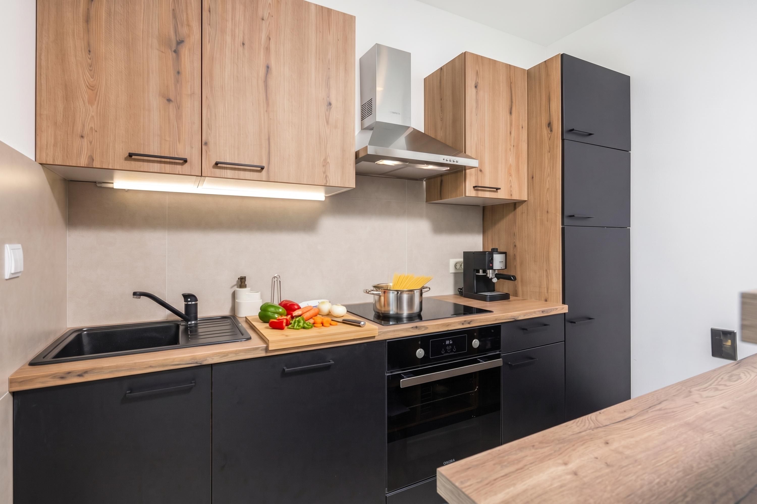 Una cocina moderna con armarios de madera, un lavamanos de acero inoxidable y un horno empotrado.