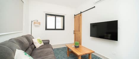 Uma sala de estar moderna com um sofá, uma mesa de centro, uma televisão e uma porta de correr.