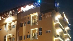Un edificio de varios pisos con balcones y un estacionamiento al frente.