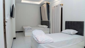 Habitación de hotel con dos camas, un espejo grande y una lámpara en el techo.