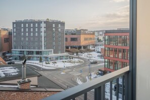 Blick auf eine Stadtlandschaft mit modernen Gebäuden, darunter ein Hotel mit Glasfassade und ein rotes Gebäude mit einem Schild.