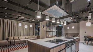 A modern kitchen with a central island, pendant lighting, and a dining area with a table and chairs.