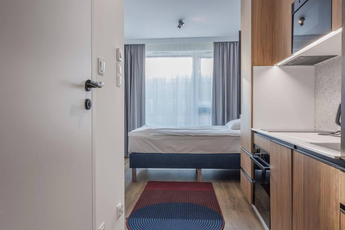 Een moderne hotelkamer met een bed, een kleine kitchenette en uitzicht op de stad.