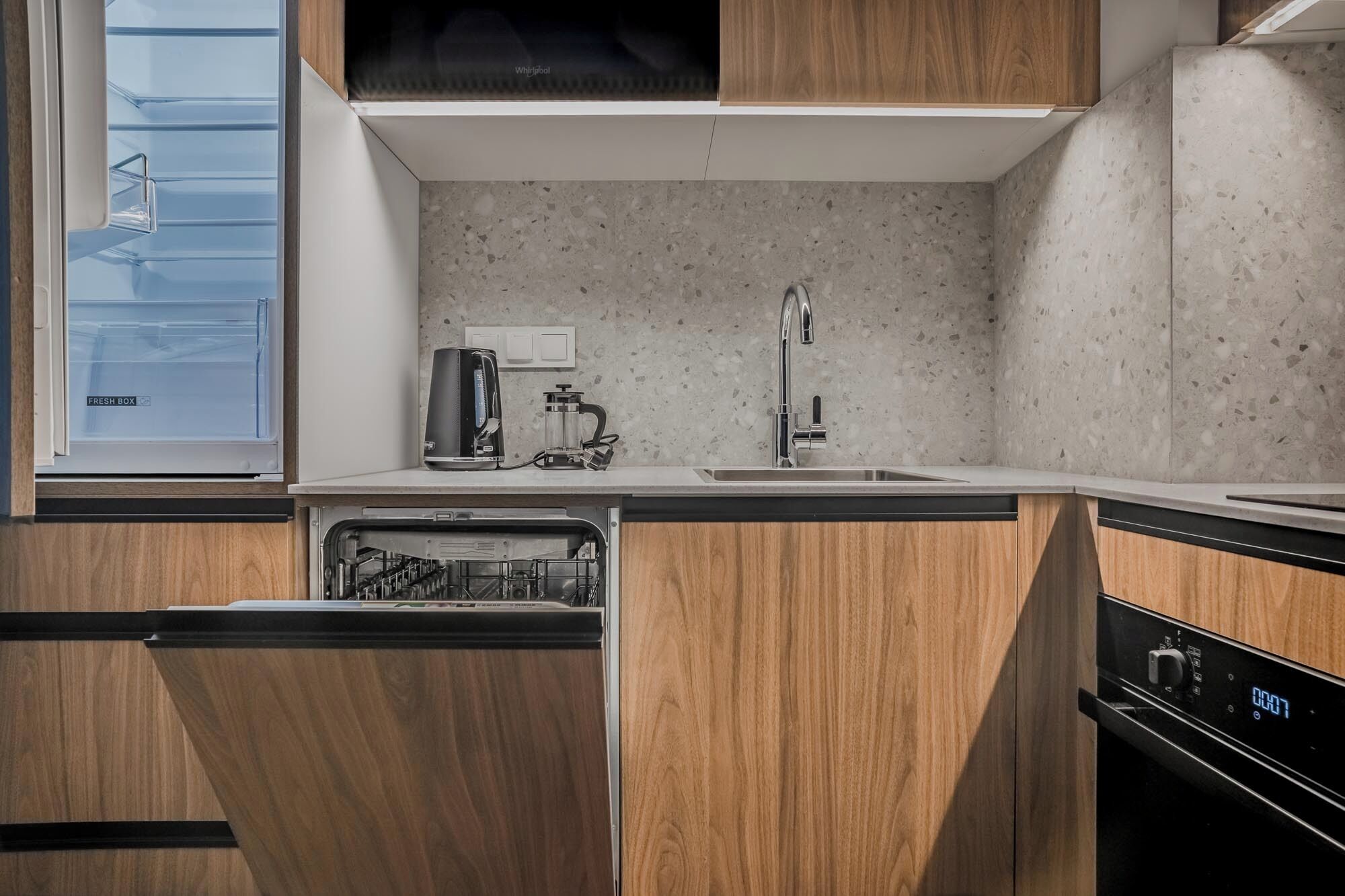A modern kitchen with a dishwasher, a coffee maker, and a sink.
