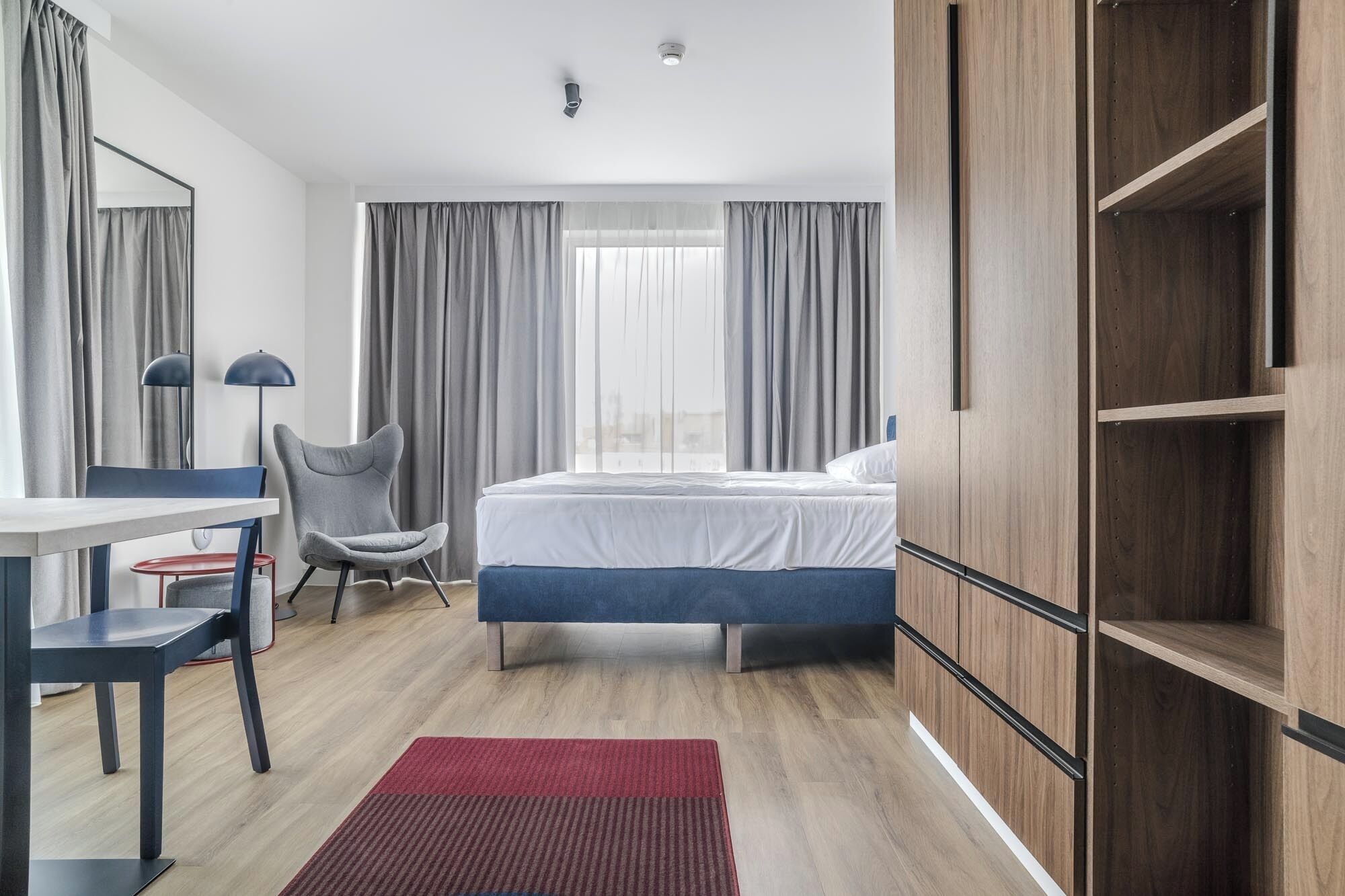 Une chambre d’hôtel moderne équipée d’un lit, d’un bureau, d’une chaise et d’une armoire.
