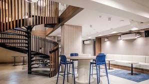 A modern interior with a spiral staircase, a round dining table with blue chairs, and a white sofa.