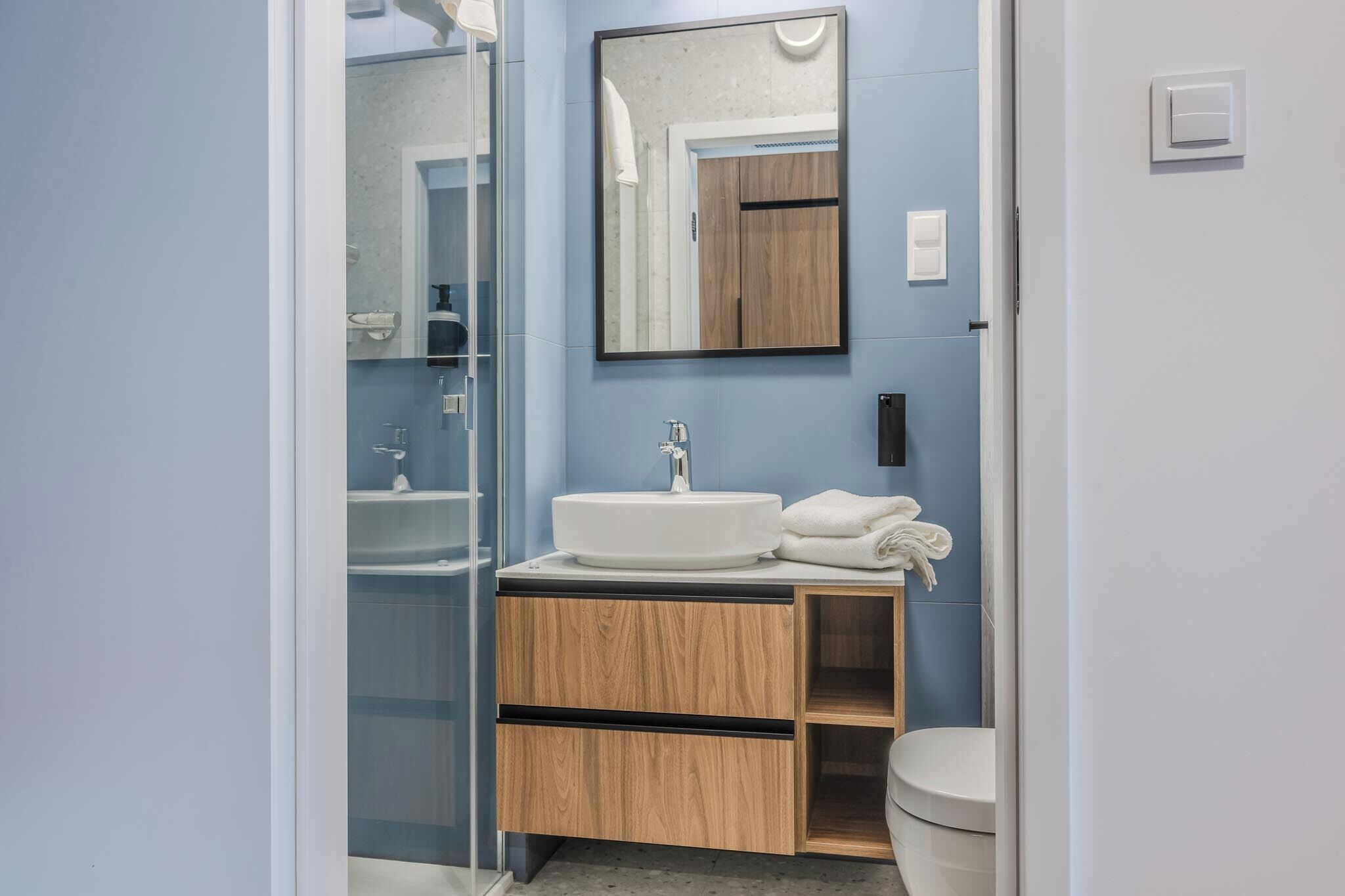 Une salle de bain moderne avec un meuble-lavabo en bois, un lavabo rond et des toilettes.