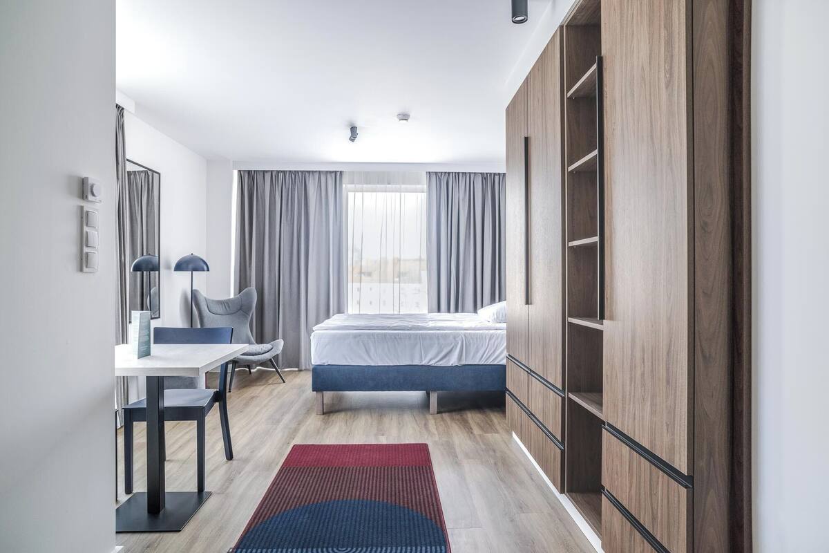 Een moderne hotelkamer met een bed, een bureau, een stoel en een kledingkast.