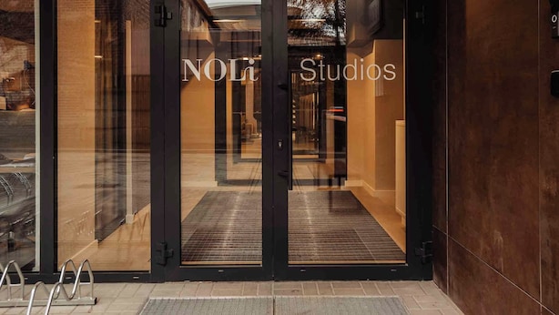 A hotel entrance with glass doors and a sign reading "NOLi Studios".