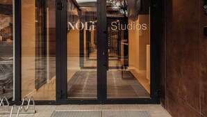 Entrada de un hotel con puertas de vidrio y un letrero que dice "NOLi Studios".