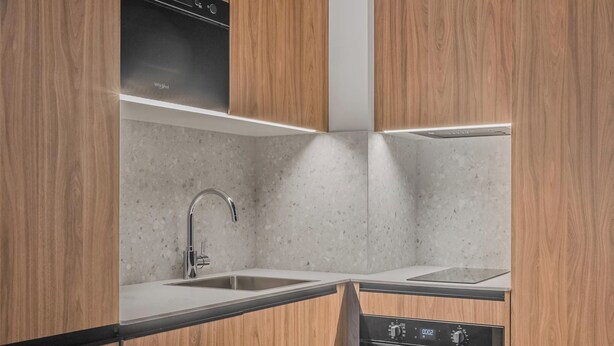 Una cocina moderna con armarios de madera, un lavamanos de acero inoxidable y un horno empotrado.