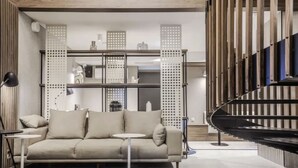 A modern living room with a beige sofa, two side tables, and a black spiral staircase.