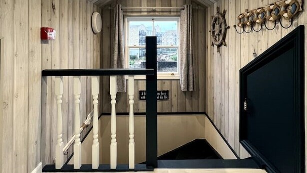 A wooden interior with a staircase, a window with a view, and a wall-mounted coat rack. - Light Bright Loft Studio with view of City & Canal (London)