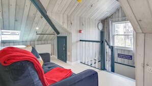 A cozy room with a high ceiling, a blue couch, a red throw blanket, and a window with a view of buildings outside. - Light Bright Loft Studio with view of City & Canal (London)