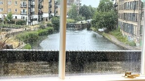 A view through a window with a brick wall and a river in the background. - Light Bright Loft Studio with view of City & Canal (London)