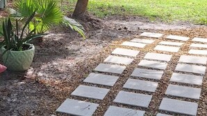 A paved pathway leading through a lush garden with palm trees and a small pond. - Beautiful Cottage! Your Home Away From Home.  4 miles from Disney, Kissimmee (Kissimmee)