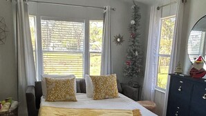 A bedroom with a bed, a ceiling fan, a Christmas tree, and a dresser. - Beautiful Cottage! Your Home Away From Home.  4 miles from Disney, Kissimmee (Kissimmee)