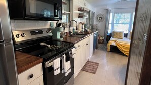 A modern kitchen with white cabinets, a black stove, and a microwave. - Beautiful Cottage! Your Home Away From Home.  4 miles from Disney, Kissimmee (Kissimmee)