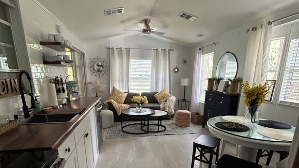 A spacious kitchen with a dining area, a sofa, and a ceiling fan. - Beautiful Cottage! Your Home Away From Home.  4 miles from Disney, Kissimmee (Kissimmee)