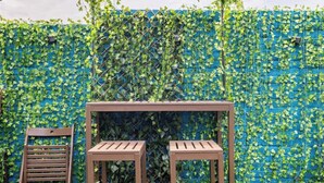 A wooden bench and chair set against a wall covered with green ivy. - Family Friendly Studio inc free Parking and Garden (London)