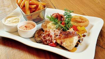 A plate of food including steak, fries, and onion rings, with two dipping sauces.
