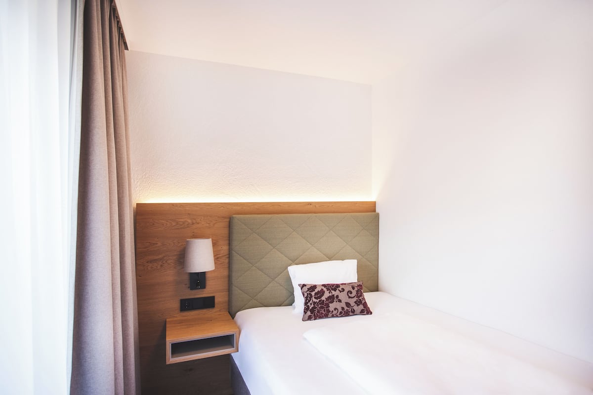 A hotel room with a bed, a nightstand, a lamp, and a headboard.