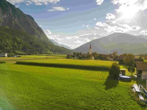 A rural landscape with a church, fields, and a mountain. - Der Dolomitenhof  (Tristach)