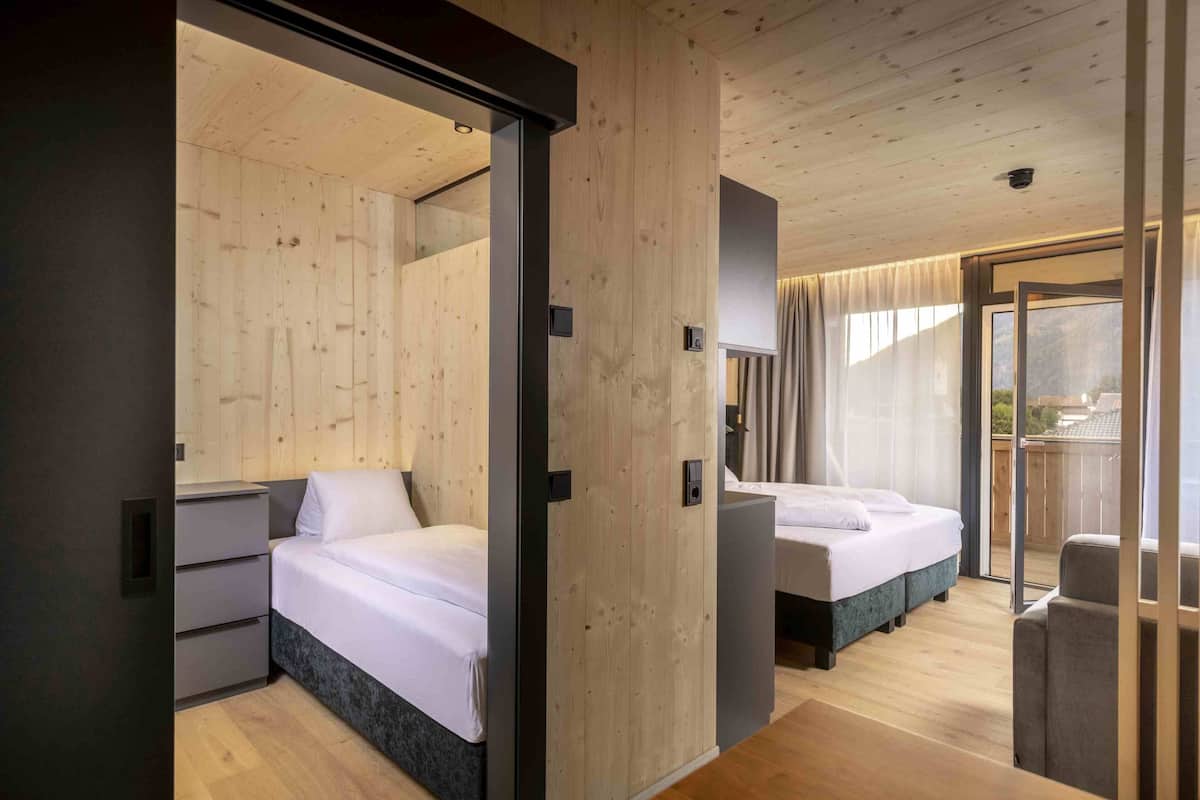 A modern bedroom with two beds, a sliding door, and a balcony with a view.