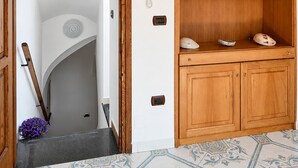 Ein Holzinnenraum mit einer Treppe, einem an der Wand befestigten Telefon und einem Regal mit Dekorationen.