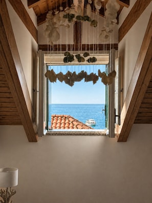 Ein Zimmer mit Meerblick durch ein Fenster mit einem dekorativen Vorhang.