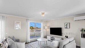 A modern living room with a sofa, TV, and a balcony with a view.