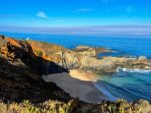 Un paysage côtier caractérisé par des falaises rocheuses, une plage de sable et l’océan.