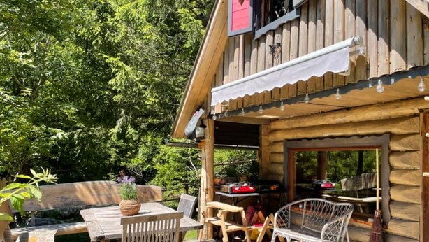 Une cabane en bois dotée d’une terrasse, d’un espace salon extérieur et d’un coin barbecue.