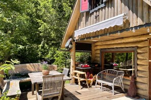 A wooden cabin with a deck, outdoor seating, and a barbecue area. - Stern House (ŽIROVNICA)