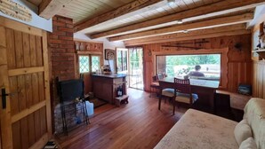 Un intérieur rustique en bois, comprenant un coin repas, une cuisine et une grande fenêtre donnant sur l’extérieur.