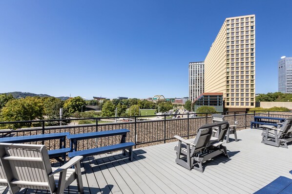 A rooftop terrace with outdoor seating and a view of a cityscape. - Sleek 2BR Downtown Retreat with Gym (Pittsburgh)