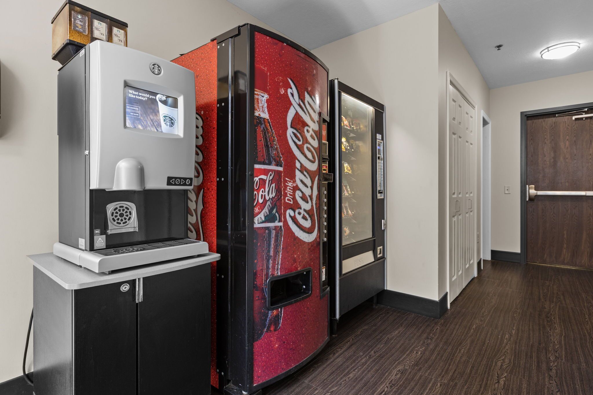 A vending machine area with a Coca-Cola branded machine and a coffee machine.