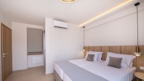 Une chambre à coucher moderne avec un grand lit, une table de chevet, un climatiseur fixé au mur et un luminaire au plafond.