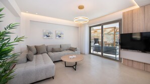 Un salon moderne avec un canapé d’angle, une table basse ronde et un téléviseur à écran plat.