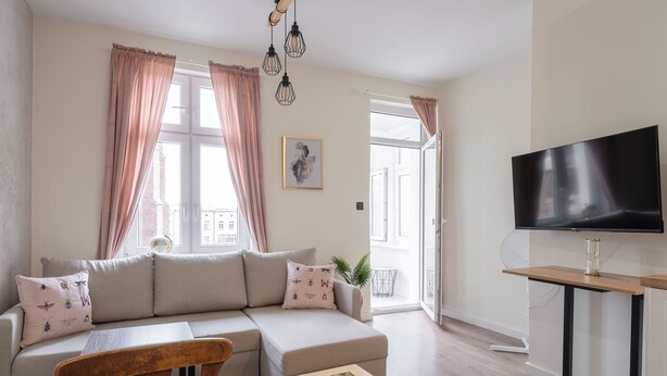 A modern living room with a sofa, a wooden table, and a TV on a stand. - RentPlanet - Apartament Świdnicka (Wroclaw)
