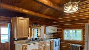 A cabin-style kitchen with wooden walls, a central island, a microwave, and a toaster.