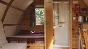 A cozy cabin interior with a wooden bed, a shower, and a kitchenette. - Cosy En-suite Glamping Cabin Near Hay-on-Wye. (Erwood)