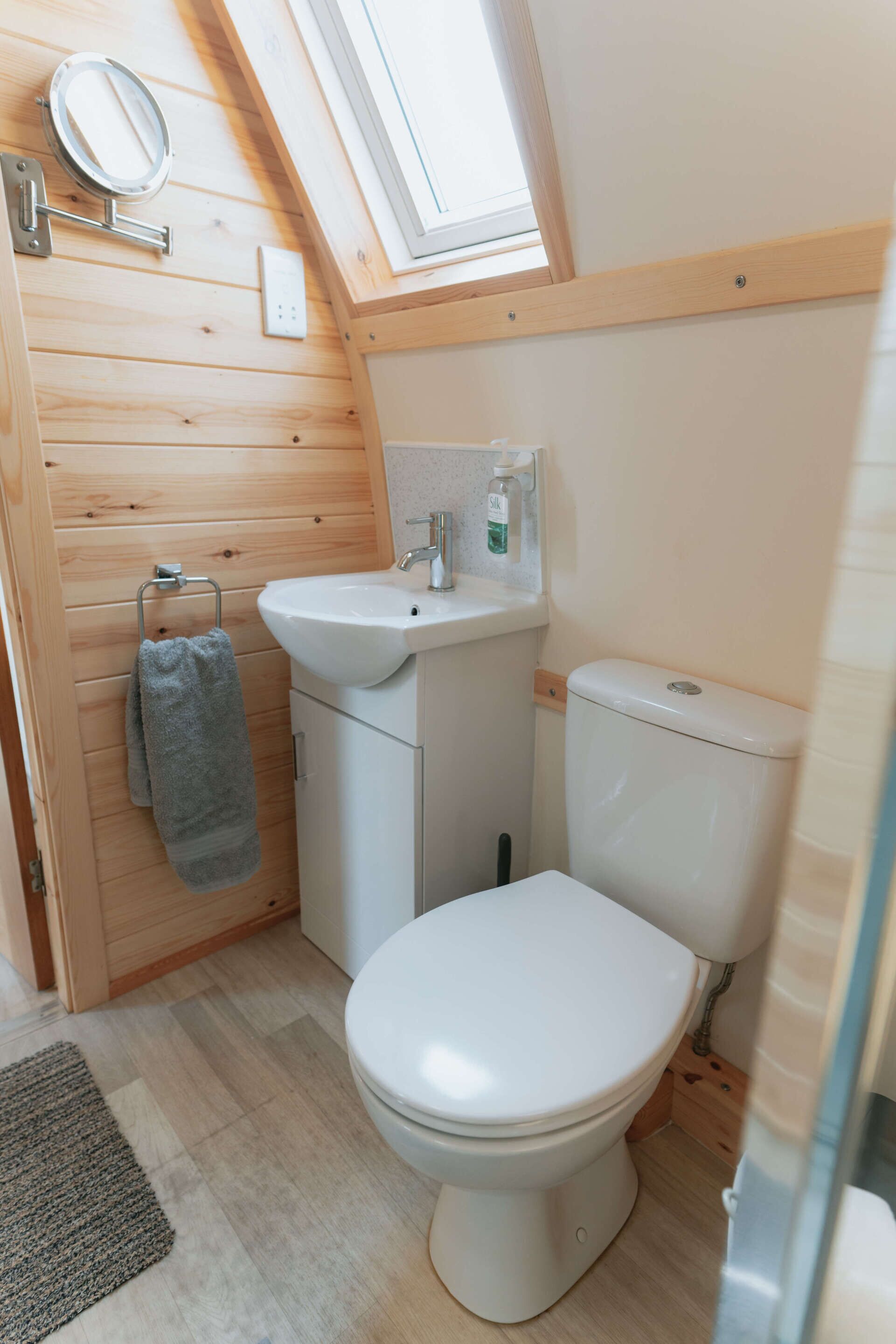 Un bagno compatto con finestra a lucernario, lavandino bianco e water.