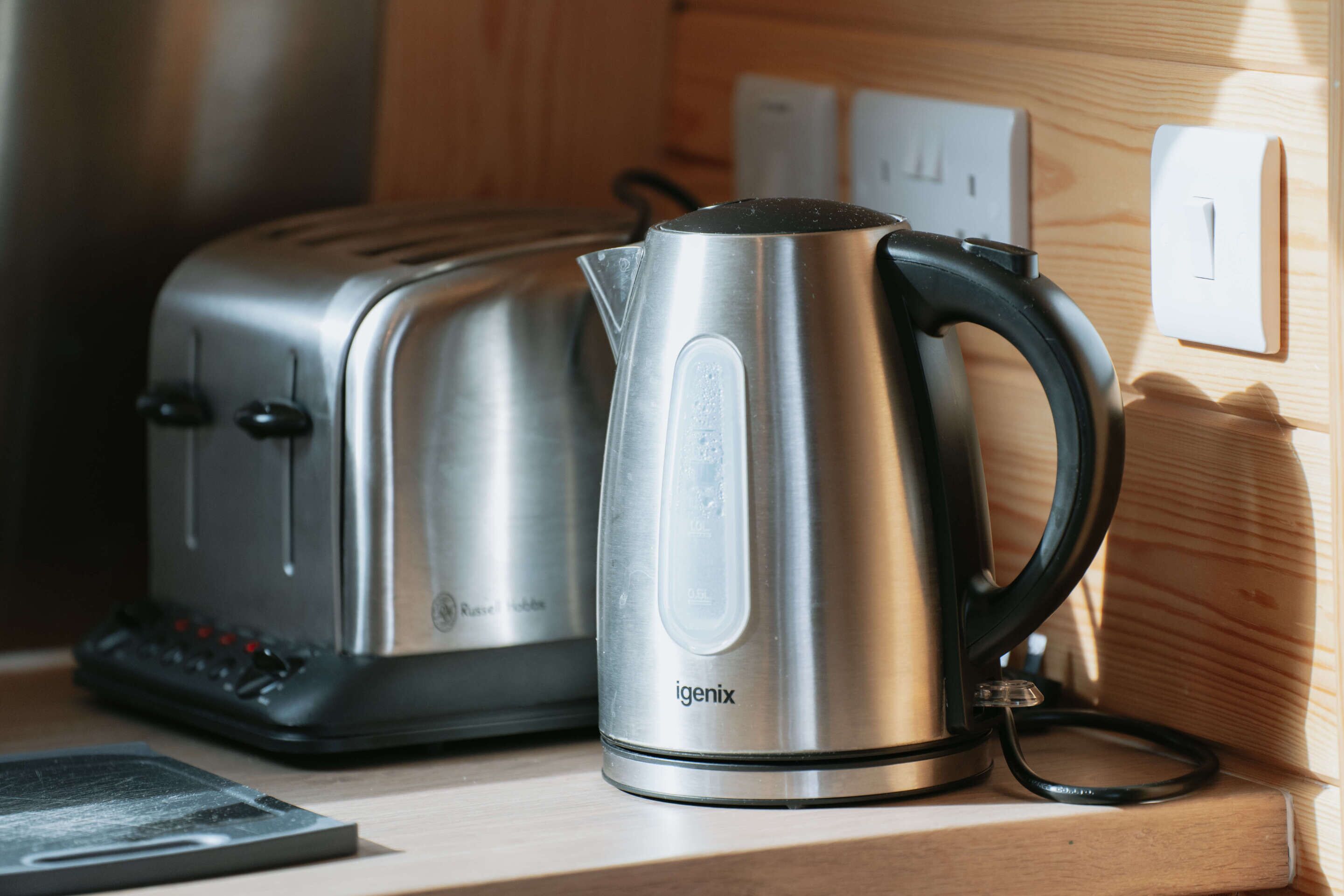 A kitchen with a toaster and a kettle on a wooden countertop.