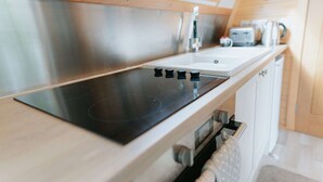 Eine moderne Küche mit einem schwarzen Induktionskochfeld, Edelstahlgeräten und einer Holzzieldecke.