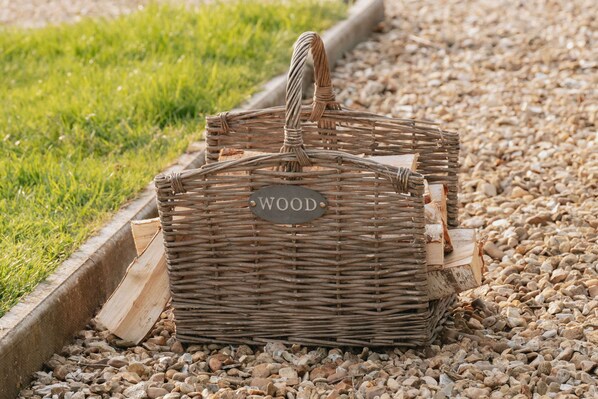 A wicker basket labeled "WOOD" on a gravel path with grass on one side.