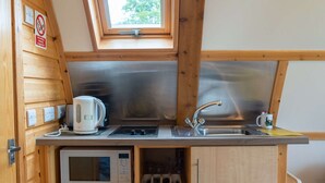 A compact kitchen with a built-in microwave, a kettle, and a sink.