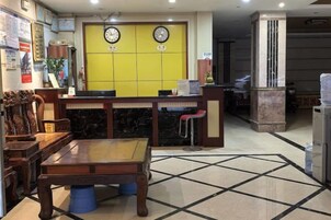 Un hall de hotel con una recepción, una mesa de madera y un suelo estampado.