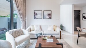 Uma sala de estar moderna com um sofá branco, uma mesa de centro de madeira e duas fotos emolduradas na parede.