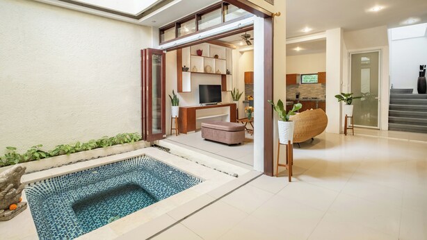 A modern interior with a swimming pool, a kitchen area, and a seating space. - The Seven Residence (Kerobokan)